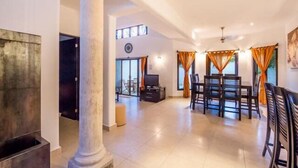 A spacious living area with a fireplace, a dining table with chairs, and a large window with curtains. - Swimming Pool, Rooftop Terrace, 4 Blocks from Ocean (Cozumel)