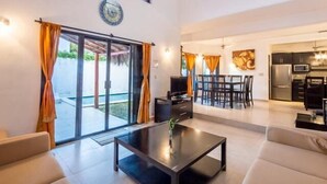A modern living room with a glass door leading to a patio, a dining area, and a kitchen. - Swimming Pool, Rooftop Terrace, 4 Blocks from Ocean (Cozumel)