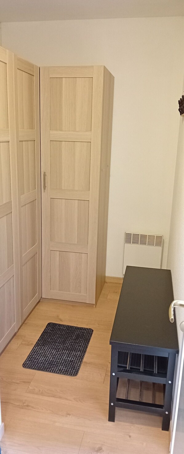 A room with a wooden wardrobe, a black table, and a radiator.