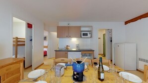 A compact kitchen with a microwave, a coffee maker, and a dishwasher. There is a dining table set with plates, glasses, and cutlery. - Balcons G 025 - PARC NAT. VANOISE appart. 8 pers. (Val Cenis)