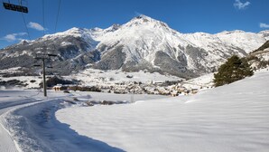 Une montagne enneigée, avec un télésiège et un village situé dans la vallée.