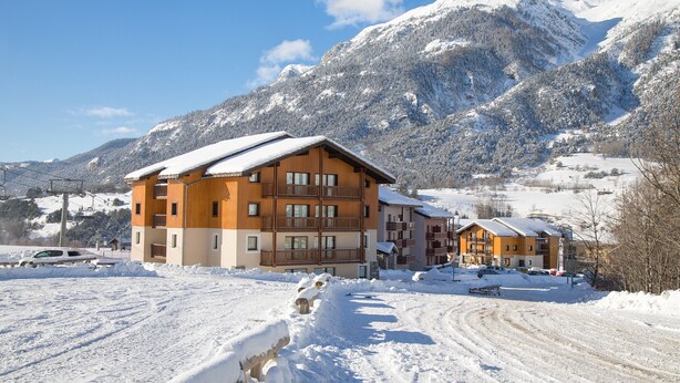 Un hôtel à plusieurs étages, doté d’une façade en bois, situé dans une région montagneuse enneigée où le ciel est dégagé.