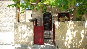 A stone building with a red gate, arched windows, and potted plants.