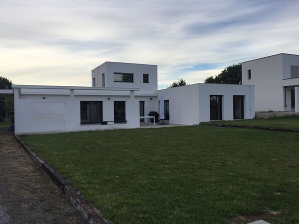 A modern two-story house with a flat roof, large windows, and a well-maintained lawn. - Modern house on La Baule international golf course (Saint-André-Des-Eaux)