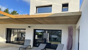 A modern outdoor seating area with lounge chairs and a pergola.