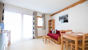 Una habitación con una mesa de comedor de madera, un sofá rojo, un banco de madera y una ventana con cortinas.