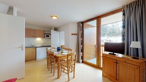 A compact living space with a dining area, kitchenette, and a large sliding glass door leading to a scenic outdoor area. - Balcons B 026 - PARC NAT. VANOISE appart. 6 pers. (Val Cenis)