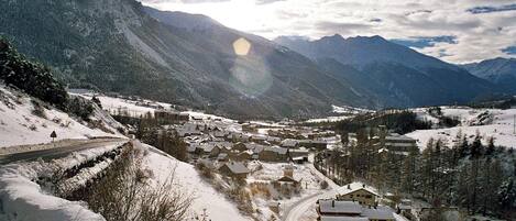 Un pueblo cubierto de nieve con casas y una carretera, rodeado de montañas.