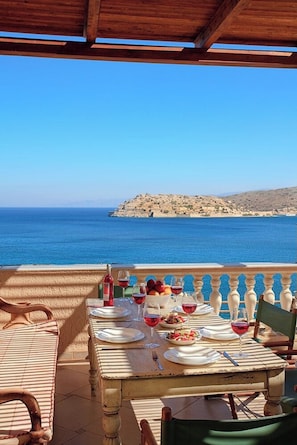 Une table dressée pour deux personnes, avec vue sur la mer et une île rocheuse.