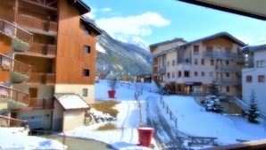A snow-covered mountain village with wooden buildings, balconies, and a ski lift.