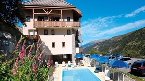 Ein zweistöckiges Hotel mit Pool, Außenbereich und Blick auf die Berge.