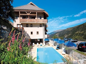 Ein zweistöckiges Hotel mit Pool, Außenbereich und Blick auf die Berge.