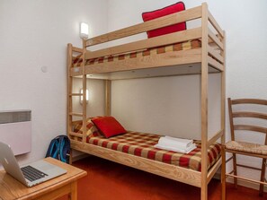 Ein Etagenbett mit einem Laptop auf einem Tisch, einem Stuhl und einem Heizgerät.