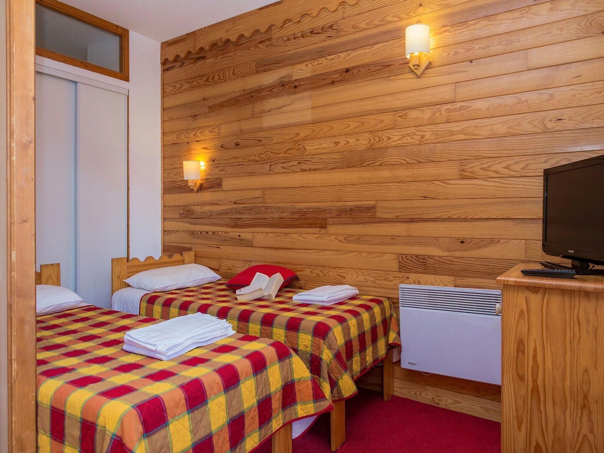 A room with two beds, a television, and a heater.