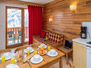 A cozy room with a wooden interior, a dining table set with breakfast, a laptop, and a coffee maker.