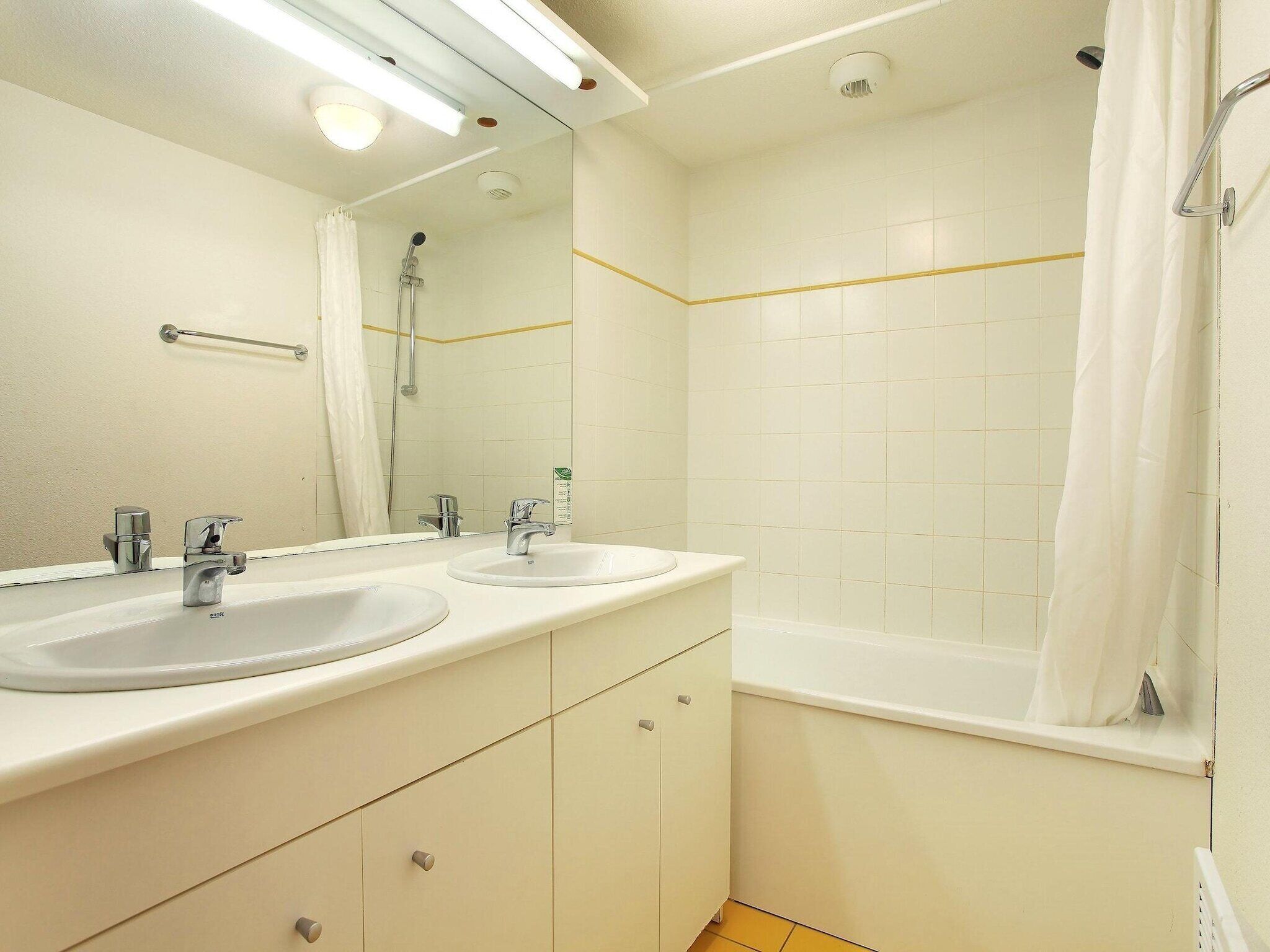 Baño con dos lavamanos, ducha y espejo.