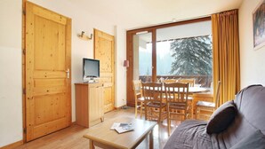 Een gezellige kamer met een houten vloer, een bank, een tafel en een televisie.