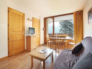Ein gemütliches Zimmer mit Holzboden, einer Couch, einem Tisch und einem Fernseher.