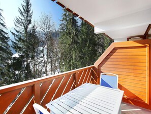 A wooden deck with a table and chairs, overlooking a forested area.