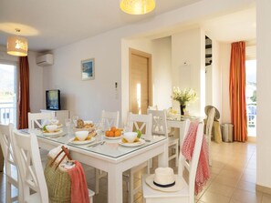 A dining area with a glass table, white chairs, and a television on the wall. - Apartment in Corsica near Beaches (Oletta)