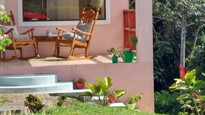 Une maison moderne avec une grande fenêtre, un fauteuil à bascule en bois et plusieurs plantes en pot.