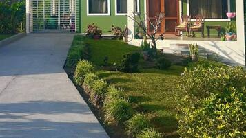 A two-story house with a green and white exterior, a covered porch, and a driveway leading to the entrance.
