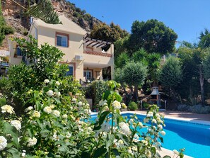 A poolside view of a building with a pergola, surrounded by lush greenery and a clear blue sky. - Luxury Villa with Private Pool, nr Malaga and Marbella. 2 beds (optional 3rd) (Malaga)