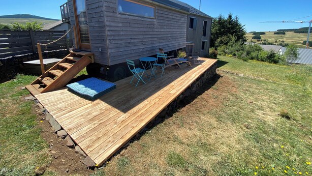 A mobile home with a deck, outdoor seating, and a scenic hillside view. - La roulotte des Estables (Les Estables)