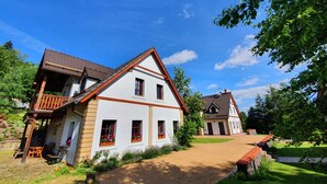 Una casa de estilo europeo tradicional con techo inclinado, balcón de madera y jardín cuidado.