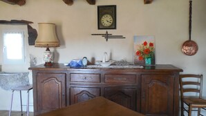 A wooden dining table with a lamp, a clock, and a painting on the wall. - $ ATYPICAL COUNTRY HOUSE (Sauvagnat)