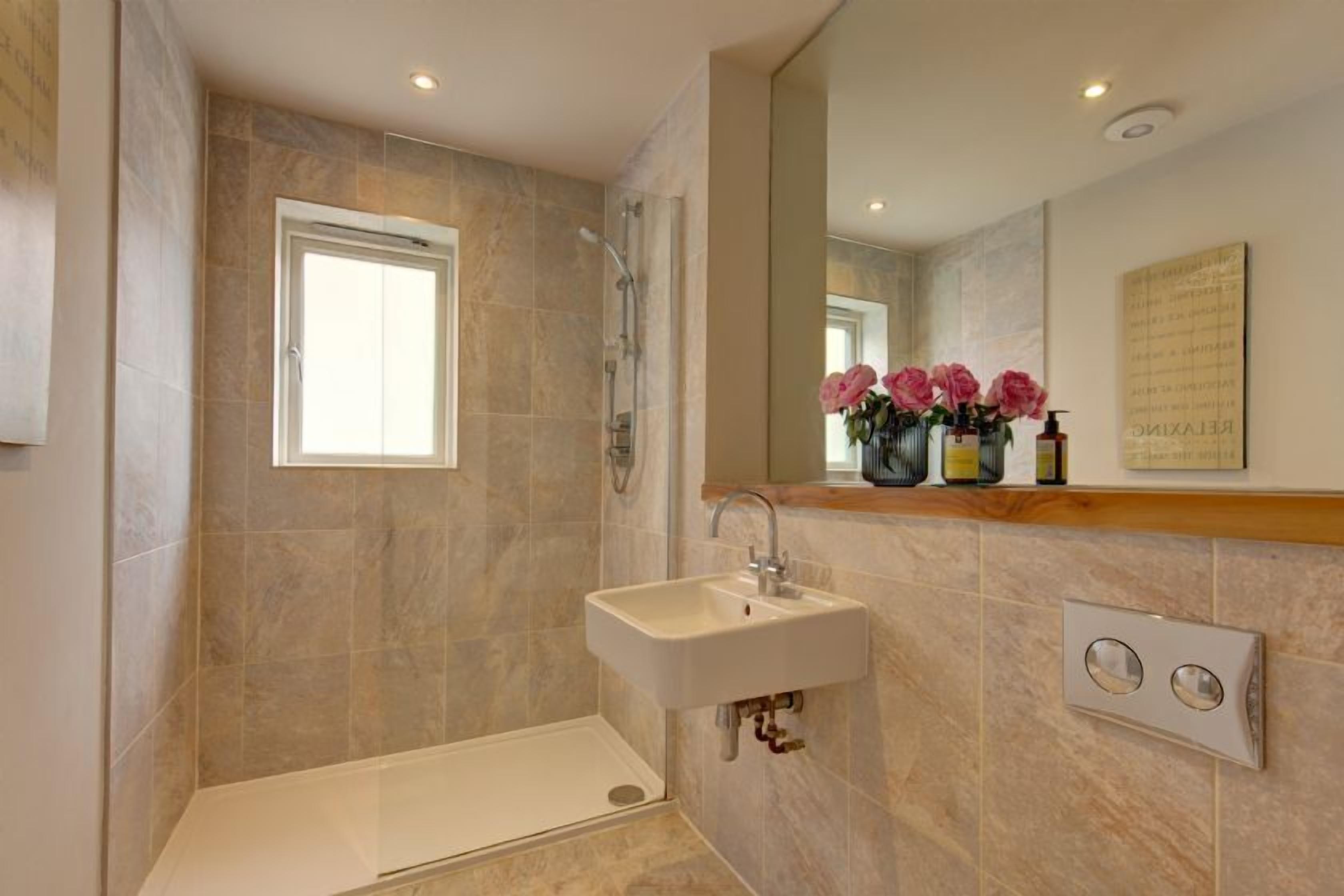 Une salle de bain moderne avec une douche, un lavabo et une fenêtre.
