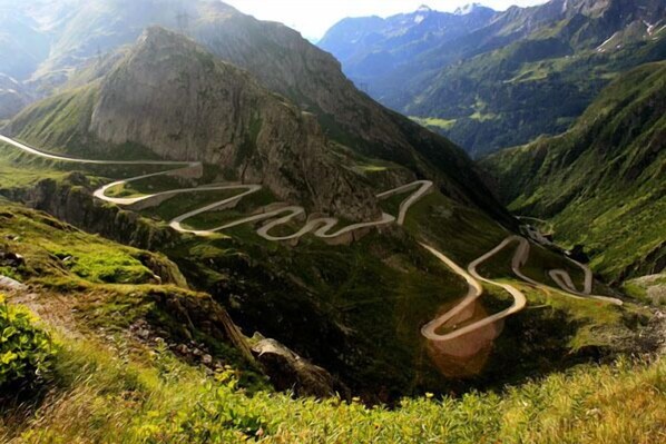 A winding mountain road surrounded by lush green hills.