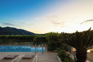 Zona de piscina con sillones de descanso y vistas a montañas.