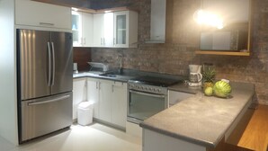 Eine moderne Küche mit Edelstahlgeräten, weißen Schränken und einer Arbeitsplatte aus Granit.