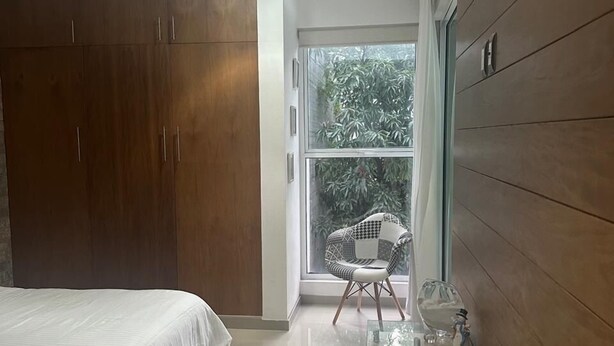 Ein Schlafzimmer mit Bett, Kleiderschrank und einem kleinen Tisch mit Glasplatte.