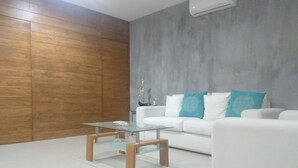 Ein modernes Wohnzimmer mit einem weißen Sofa, einem Glastisch und einer grauen Akzentwand.