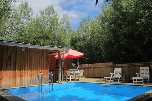 Lodge en bois avec terrasse et  piscine dans un cadre verdoyant
