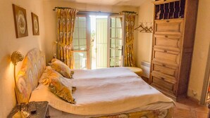 A bedroom with a bed, a nightstand, a dresser, and a window with curtains.