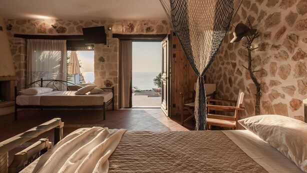 Een slaapkamer met een bed, een stoel en uitzicht op zee.