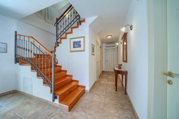 A staircase with wooden steps and metal railings, leading to a hallway with a door and a small table with a vase. - Villa Mir Vami near the beach, private pool, Sumartin, Brac Island (Sumartin)
