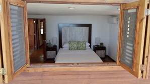 A wooden-framed bedroom with a large bed, two bedside tables, and a wooden floor.