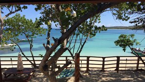 A beach view with a wooden deck, a hammock, and a bench.