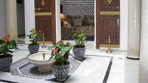 A courtyard with a fountain, potted plants, and traditional doors. - Beau Riad for Rent (Fès-Boulmane)