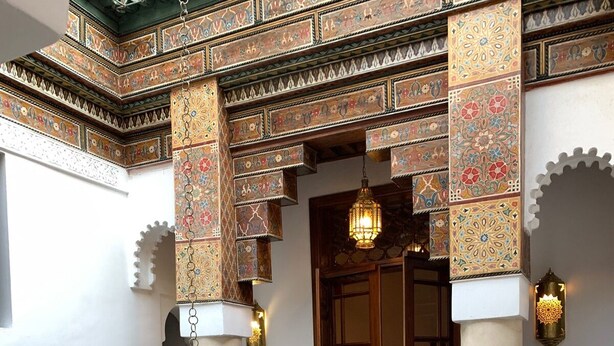 A traditional interior with ornate tile work, a hanging lantern, and a balcony with a wooden railing. - Beau Riad for Rent (Fès-Boulmane)