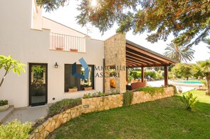 A modern house with a stone facade, a covered patio, and a swimming pool.