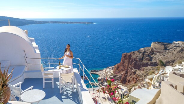 Une terrasse meublée de mobilier blanc, offrant une vue sur la côte.