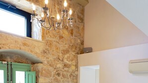 Una habitación con pared de piedra, una puerta verde, un sofá con cojines coloridos y una mesa con cuencos.
