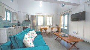 A compact living space with a kitchenette, a dining area, and a sofa with patterned cushions.