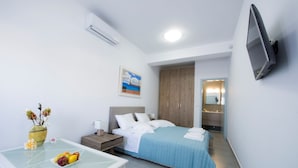 A hotel room with a bed, bedside table, TV, and a bathroom visible through an open door.