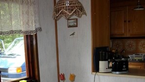 Un coin repas comprenant une table et quatre chaises, un vase avec des fleurs et une fenêtre donnant sur une voiture garée.